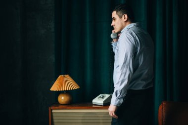 Özel ajan eski telefonla konuşuyor. Casusluk ya da istihbarat toplama. Casusluk konsepti. Bilgileri üstlerinize bildirin.