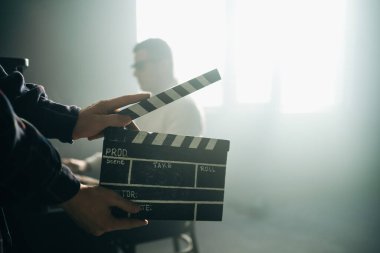 El çırpma tahtası ya da pano ellerinde. Adam retro sinema ya da klasik filmi yönetiyor ve filme alıyor. Besteci adam eski piyanoda çalıyor..