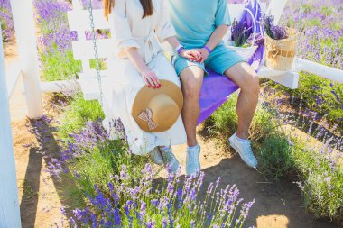 Beyaz ahşap bankta kucaklaşan çift, romantik bir aşk hikayesi. Yaz tarlasında güzel mor lavanta çiçekleri. Sıcak ve ilham verici kavram.