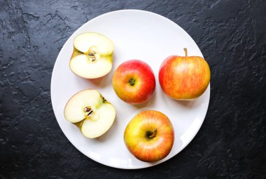 Apples lying on the white plate. Still life photo. Black background.