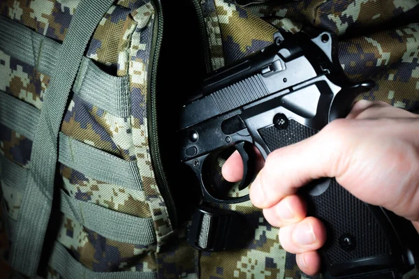 stock image Man is putting in a military backpack Pistol or Gun