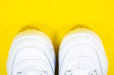 Modern sneakers on the yellow background. White leather trainers on big sole with spikes. Close up.