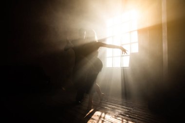 İki profesyonel balo dansçısı çatı katında dans ediyor. Ağır dumanla güzel bir sanat gösterisi. Spor hayatı konsepti. Tutku ve duygusal dans.