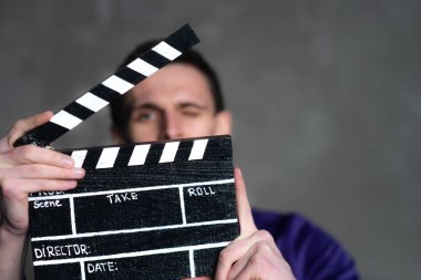 Adam elinde klasör ya da pano tutuyor. Adam bir sinema filmi çekiyor ve yönetiyor..