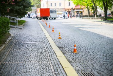 Taş yolda trafik konileri var. Park işareti yok..