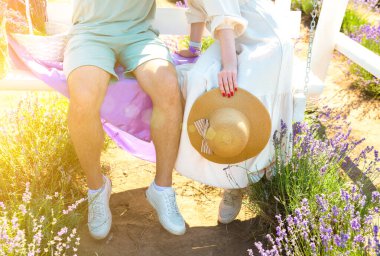 Beyaz ahşap bankta kucaklaşan çift, romantik bir aşk hikayesi. Yaz tarlasında güzel mor lavanta çiçekleri. Sıcak ve ilham verici kavram.