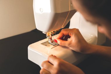Kadın dikiş makinesine iplik koyuyor. Serbest çalışan kızlar ellerini kullanıyor. Moda konsepti. Yeni kıyafet süreci oluşturuluyor. Hobi fikirleri.