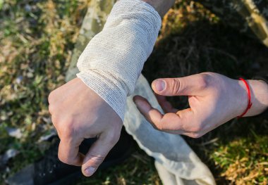 Adam burkulmuş bileğe bandaj yapıyor. Kolum burkuldu. Doğada yaralı bir turist. Yürüyüş.