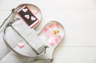 Telefon, şık çanta ve beyaz arka planda parfümler. Kalpli güzel bir daire. Kız için en iyi hediye. Kadınların ya da annelerin günü fikri..