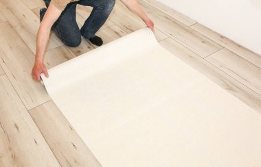 Adam yerde yuvarlak duvar kâğıtlarını tutuyor. Bakım onarımı dairede tadilat yapıyor. İçerideki restorasyon.