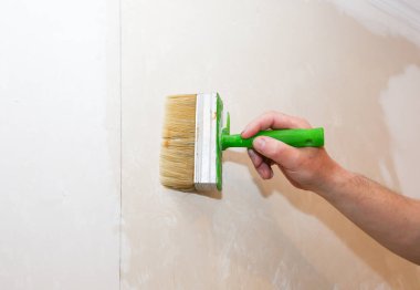 Adam duvara fırçayla yapıştırıcı sürüyor. Duvar kâğıdı asılı. Bakım onarımı dairede tadilat yapıyor. İçerideki restorasyon.