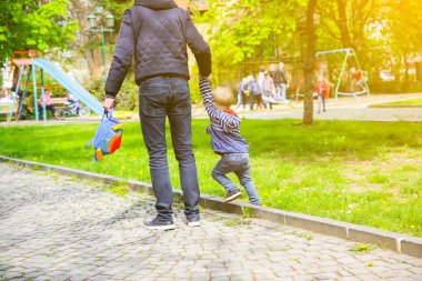 Baba oğluyla çocuk parkında yürüyor..