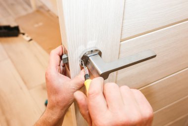 Adam kapı kolunu kuruyor. Onarım işe yarıyor. Dairede bakım var..