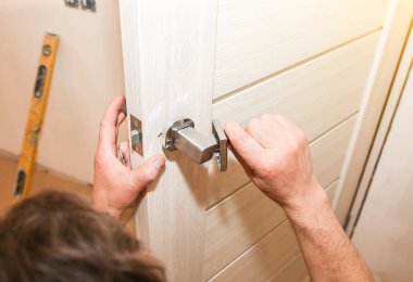 Adam kapı kolunu kuruyor. Onarım işe yarıyor. Dairede bakım var..