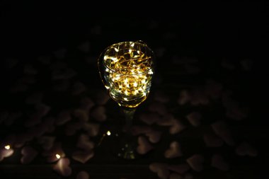 Şarap kadehindeki ışıklar. Kalpler arka planda. Romantik aşk kavramı. Şenlikli fikirler. Sevgililer Günü kartpostalı.