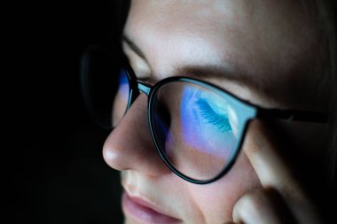 Gözlüklü yorgun kadın internette çalışıyor. Bütün gün bilgisayarın önünde migren ya da baş ağrısı. Göz ağrısı, kuru göz sendromu..