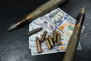 Dolar parası, mermi, kovan, fişekler ve siyah arka plandaki mermiler. Kira sözleşmesi konsepti. Ordu konsepti. Silah ve mühimmat satışı