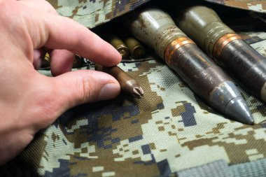 Asker, haki rengi kamuflaj çantasındaki mermileri, mermileri ve mermileri tutar. Kira sözleşmesi konsepti. Ordu konsepti. Silah ve mühimmat satışı. Askeri sanayi, savaş, küresel silah ticareti.