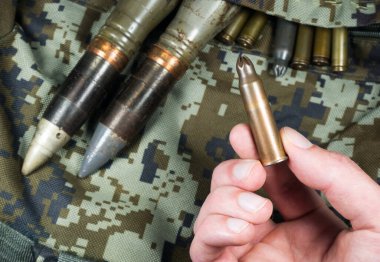 Asker, haki rengi kamuflaj çantasındaki mermileri, mermileri ve mermileri tutar. Kira sözleşmesi konsepti. Ordu konsepti. Silah ve mühimmat satışı. Askeri sanayi, savaş, küresel silah ticareti.