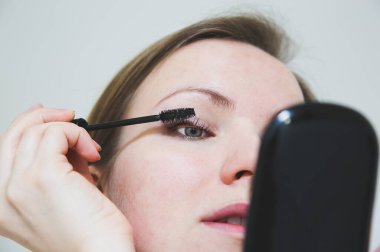 Kız makyaj yapıyor. Kirpiklerde siyah rimel. Güzellik fotoğrafı konsepti.