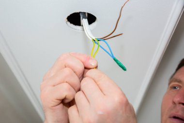 Adam elektrikli yalıtkan yapıyor. Yapışkan bantlı ampul telleri. Bakım onarımı dairede işe yarıyor. İçerideki restorasyon.