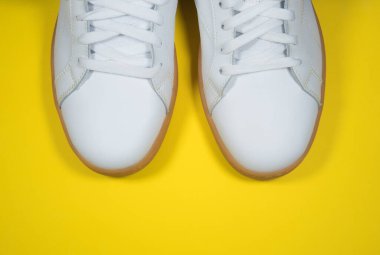 Sarı arka planda modern spor ayakkabılar. Sarı tabanlı beyaz deri ayakkabılar. Kapat..