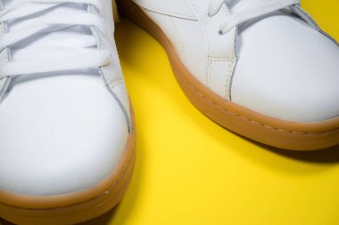 Sarı arka planda modern spor ayakkabılar. Sarı tabanlı beyaz deri ayakkabılar. Kapat..
