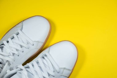 Sarı arka planda modern spor ayakkabılar. Sarı tabanlı beyaz deri ayakkabılar. Kapat..