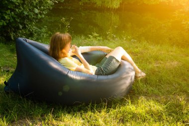 Vahşi kampta şişme koltukta dinlenen bir kadın.