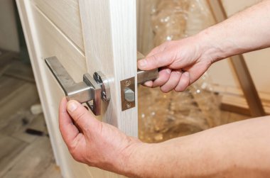 Adam kapı kolunu kuruyor. Onarım işe yarıyor. Dairede bakım var..