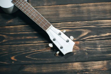 Kahverengi ahşap arka planda beyaz renkli ukulele gitar. Hawaii dört telli gitarı. Müzik Aracı.