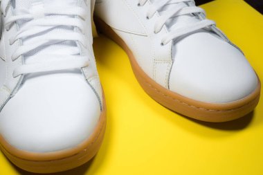 Sarı arka planda modern spor ayakkabılar. Sarı tabanlı beyaz deri ayakkabılar. Kapat..