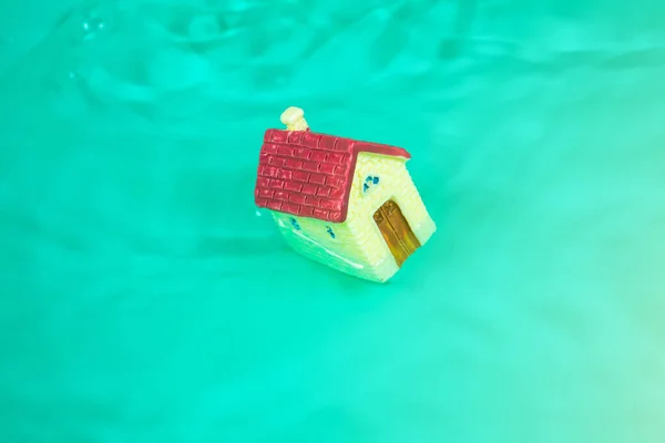 Toy house in the water. Flood concept. Insurance property. Creative idea.