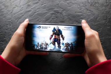 LVIV, UKRAINE - November 08, 2022 : Playing mobile game Assassin Creed: Valhalla on modern smartphone.