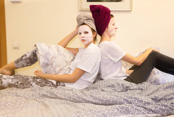 Girls in skin mask sheet on face. Beauty procedures at home. Hen party. Women having fun.