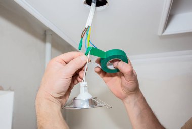 Adam elinde yapışkan bant tutuyor. Ampul için elektrik yalıtkan. Bakım onarımı dairede işe yarıyor. İçerideki restorasyon.