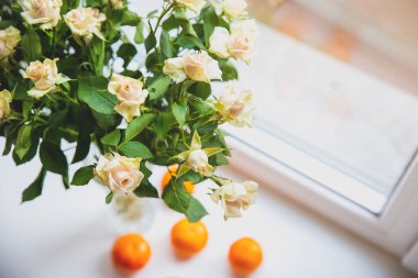 Roses with tangerines on window sill. Healthy and beautiful lifestyle. Cosy home ideas.
