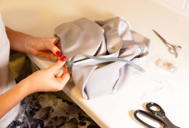 Woman is sewing a dress. Needle and thread in girl's hands. Fashion concept. Freelance work at home. Creating of new clothes process. Hobby ideas.