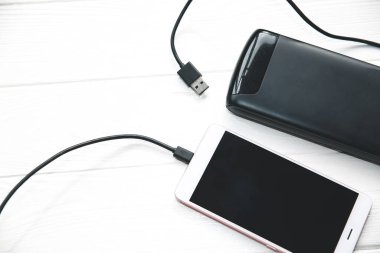 USB ve ahşap arka planda akıllı telefonları olan siyah bir güç bankası. Modern bilgi teknolojisi fotoğrafı.