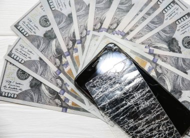 Kırık ekran koruyucu sertleştirilmiş cam. Telefonun yanında para var. Dolar banknotları.