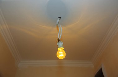 Tavanda kablolar olan yeni bir ampul. Dairede elektrik bakım onarımı yapılıyor. İçerideki restorasyon.