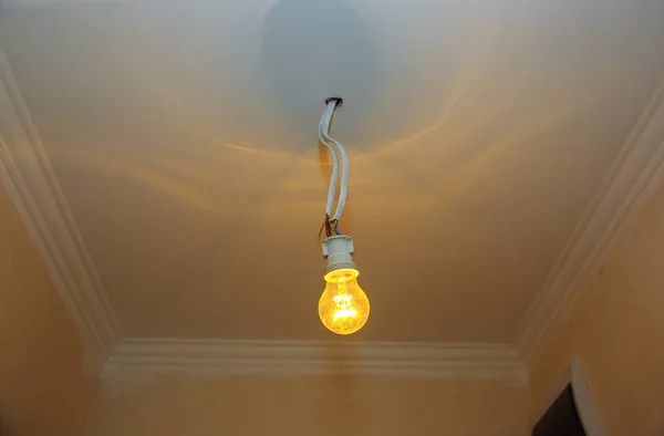 New light bulb with wires in the ceiling. Electricity maintenance repair works in the flat. Restoration indoors.