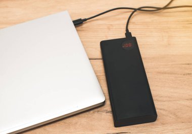 USB-C kablosu olan güç bankası dizüstü bilgisayarı şarj ediyor. Modern, bilgi teknolojisi.