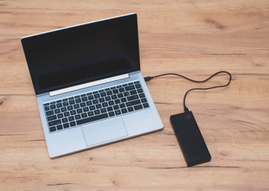 USB-C kablosu olan güç bankası dizüstü bilgisayarı şarj ediyor. Modern, bilgi teknolojisi.