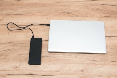 USB-C kablosu olan güç bankası dizüstü bilgisayarı şarj ediyor. Modern, bilgi teknolojisi.