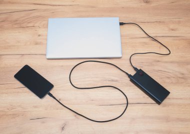 USB-C kablosu olan güç bankası dizüstü bilgisayarı ve akıllı telefonu şarj ediyor. Modern, bilgi teknolojisi.