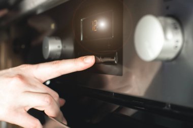 Kadın modern elektrikli fırını mükemmel yemek hazırlamak için zamanlayıcıyla ayarlıyor..