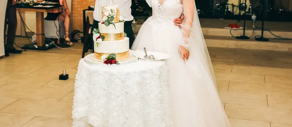 結婚式のカップルがケーキを切っている 花で飾られた美しいおいしいデザート — ストック写真