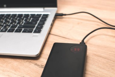 USB-C kablosu olan güç bankası dizüstü bilgisayarı şarj ediyor. Modern, bilgi teknolojisi.