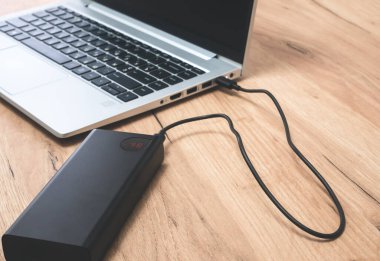 USB-C kablosu olan güç bankası dizüstü bilgisayarı şarj ediyor. Modern, bilgi teknolojisi.